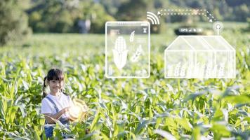 das kleine mädchen analysiert mit einem tablet das wachstum von pflanzen auf dem landwirtschaftlichen grundstück und visual icon., das landwirtschaftliche technologiekonzept. Smart-Farming-Lernkonzept foto