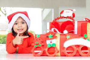 weihnachts-, feiertags- und kindheitskonzept - lächelndes mädchen mit geschenkbox zu hause foto