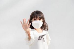 zurück zur schule.kleines asiatisches mädchen, das zum schutz eine maske trägt. Zeigen Sie die Stopp-Hand-Geste, um den Ausbruch des Coronavirus zu stoppen. foto
