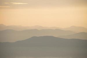 Schicht aus Bergen und Nebel während des Sonnenuntergangs foto