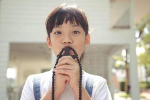 Kleines asiatisches Mädchen, das mit dem Halten des Kreuzes betet, christliches Konzept. foto