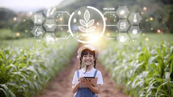 das kleine mädchen analysiert mit einem tablet das wachstum von pflanzen auf dem landwirtschaftlichen grundstück und visual icon., das landwirtschaftliche technologiekonzept. Smart-Farming-Lernkonzept foto