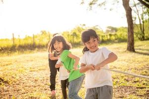 Kinder spielen Tauziehen im Park auf Sunsut foto