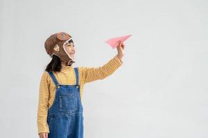 glückliches asiatisches kind, das mit einem papierflugzeug spielt foto