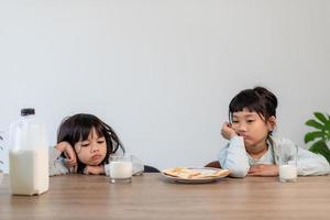 Müde Geschwistermädchen schliefen beim Frühstück ein foto