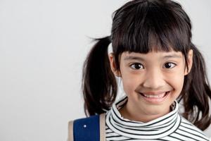 Porträt eines asiatischen Kindes in Schuluniform mit Schultasche auf weißem Hintergrund foto