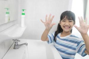 kleine asiatische mädchen waschen sich die hände im badezimmer. Weicher Fokus. Platz kopieren. foto