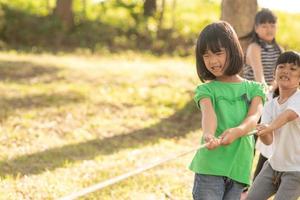 Kinder spielen Tauziehen im Park auf Sunsut foto