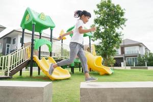 Kind spielt auf Spielplatz im Freien. kinder spielen auf dem hof der schule oder des kindergartens. aktives kind auf bunter rutsche und schaukel. gesunde sommeraktivität für kinder. foto