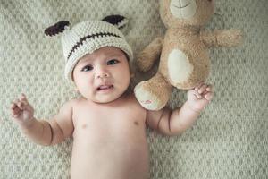 neugeborenes baby auf einer decke mit einem teddy foto