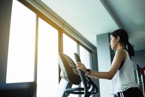 asiatische Mädchen trainieren elliptische Cardio-Lauftraining im Fitness-Studio unter Gewichtsverlust mit Aerobic-Maschine für einen schlanken und festen gesunden Lebensstil foto