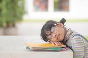Porträt eines glücklichen kleinen asiatischen Kindes, das auf einem Buch schläft foto