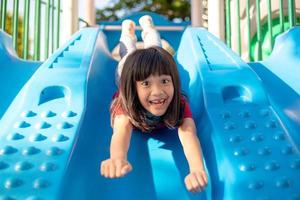 süßes kleines Mädchen, das sich im Sommer auf einem Spielplatz im Freien amüsiert foto