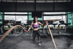 thletische junge Frau, die einige Crossfit-Übungen mit einem Seil im Freien macht foto