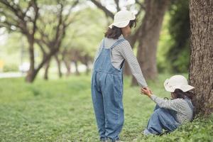 süßes asiatisches mädchen gibt hand, um schwesterunfall zu helfen foto