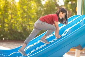 süßes kleines Mädchen, das sich im Sommer auf einem Spielplatz im Freien amüsiert foto