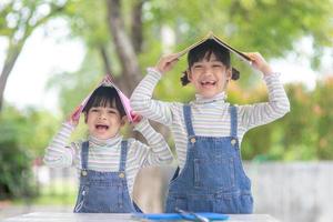 süße asiatische kinder, die ein buch auf dem tisch lesen foto