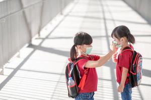 Kleines Mädchen und Schwester mit Gesichtsmaske, die während des Ausbruchs des Coronavirus zur Schule gehen. Sicherheitsmaske zur Vorbeugung von Krankheiten. mutter und kind in der schule während der covid 19 pandemie. foto