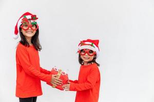 geschwister asiatische mädchen in roter weihnachtsmütze mit geschenkboxen auf weißem hintergrund. foto