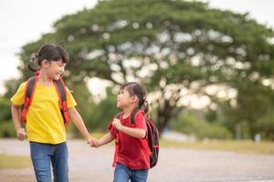 süße asiatische kinder, die hand zusammenhalten, während sie zur schule gehen foto