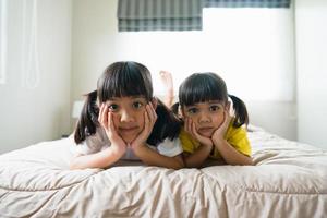 süße asiatische kinder, die auf dem bett liegen foto