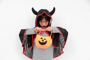 Lustiges Halloween-Kind-Konzept, kleines süßes Mädchen mit Kostüm-Halloween-Geist beängstigend, das er orangefarbenen Kürbis-Geist auf der Hand hält, auf weißem Hintergrund foto