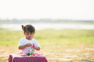 süßes kleines Mädchen spielt gerne Play Doh im Park foto