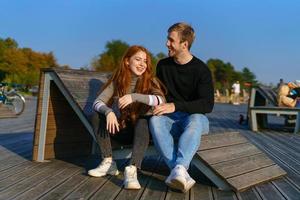 junge paare sitzen im park auf einer holzbank und umarmen sich foto