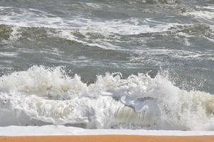 Meereswellen, die am Strand krachen foto