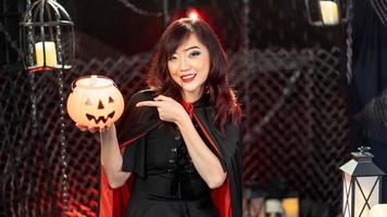 glücklicher halloween-tag. porträt asiatisch schöne frau modell als hexe kostüm lächeln gekleidet und kürbis in halloween-thema halten. foto