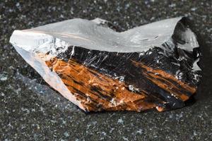 unpolierter Mahagoni-Obsidian auf schwarzem Granit foto