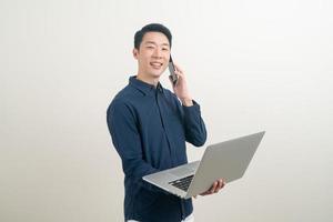 asiatischer Mann spricht Smartphone oder Handy und Hand hält Laptop foto