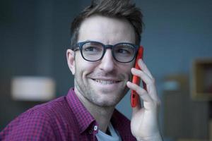 Nahaufnahme eines jungen, gutaussehenden, fröhlichen deutschen Mannes mit Brille, der telefoniert foto