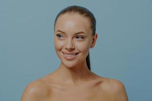 junges charmantes mädchenmodell mit natürlichem make-up und gesunder glühender haut, die isoliert auf blau posiert foto