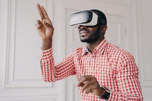 Beeindruckter Afrikaner mit Vr-Headset-Brille, der virtuelle Realität online bei der Arbeit genießt foto