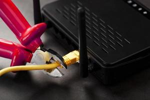 Trennen der Internetverbindung, Abschneiden des gelben Ethernet-Kabels mit Drahtschneider mit rotem Griff am Wi-Fi-Router. foto