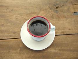 eine tasse schwarzen kaffees auf einem tisch aus holzbohlen foto