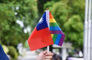 regenbogenflagge und taiwanesische nationalflagge in der hand halten, weicher und selektiver fokus, konzept zur feier von lgbtq plus im stolzmonat auf der ganzen welt. foto