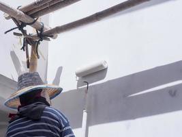 ein Maler streicht die Fassade unter der Traufe eines grauen Betondachs. foto