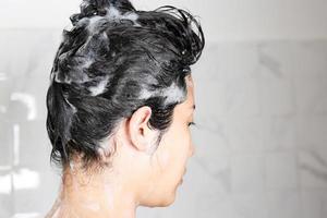 asiatische frau, die ihre haare beim duschen wäscht. foto