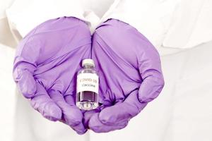 covid-19-impfstoff in den händen einer forscherin, die eine spritze und eine flasche medikamente mit impfstoff zur injektion von immunität gegen covid 19 hält foto