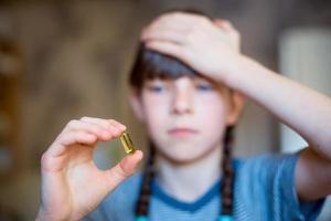 Mädchen hält eine Pille in der Hand, Kopfschmerzen und Erkältung foto