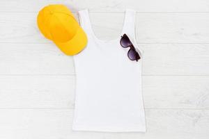 Weißes Nahaufnahme-T-Shirt mock-up flach lag auf weißem Holzhintergrund. draufsicht und kopierraum. modell sommer t-shirt und sommerzeit. Vorlage leeres Shirt. foto