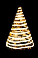 Defokussierte Lichter spiralförmiger Weihnachtsbaum auf schwarzem, isoliertem Hintergrund. Gestaltungselement. Neujahr. Platz kopieren foto