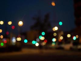 unscharfer Hintergrund. verschwommene abendliche Straßenansicht mit Ampeln und Punkten von Stadtlichtern foto