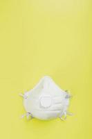 eine maske zum schutz des atems vor luftverschmutzung oder einem ausbruch von grippe oder virus auf gelbem hintergrund. foto