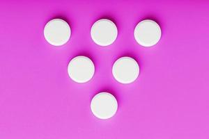 Runde Ecstasy-Tabletten in Form eines Dreiecks auf rosafarbenem Hintergrund foto