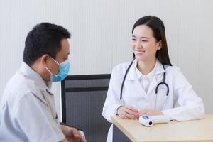 asiatische Ärztin spricht und ermutigt mit einem männlichen Patienten foto