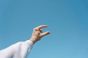 Hand in die Luft gestikulierend in den blauen Himmel, blauer Hintergrund foto