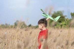 Junge spielt gerne mit Spielzeugflugzeug in der Natur und klarem Morgenhimmel, Kinderkonzept und Traumflugzeug, um Pilot zu werden. möchte wie ein Flugzeug fliegen foto